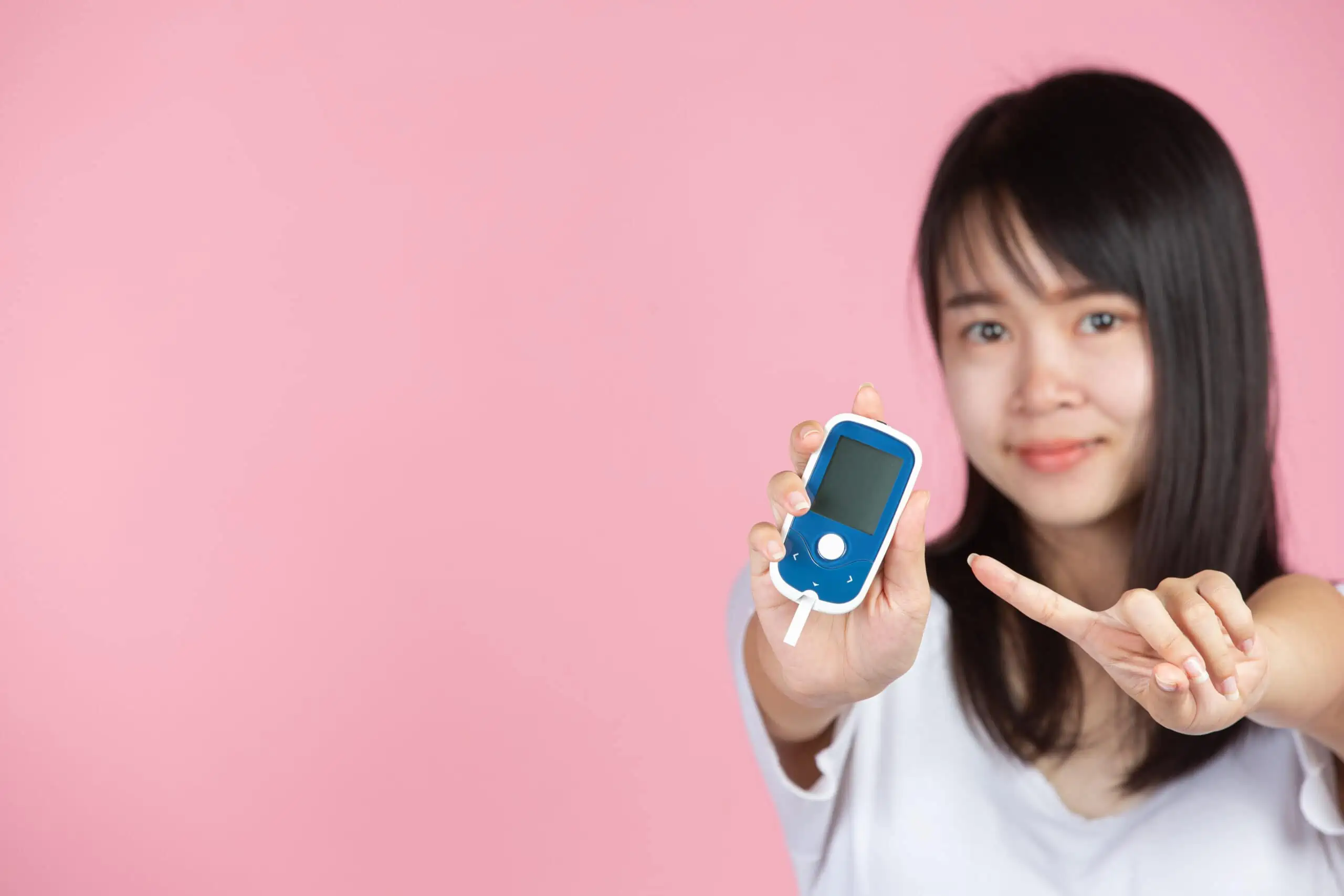 World diabetes day; woman holding Glucose meter on pink background